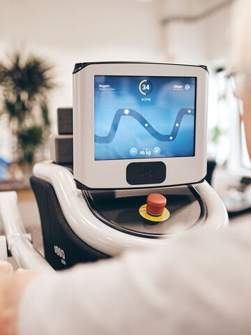 Ein älterer Mann nutzt ein Fitnessgerät mit einem digitalen Bildschirm zur Anzeige seines Trainingsfortschritts.
