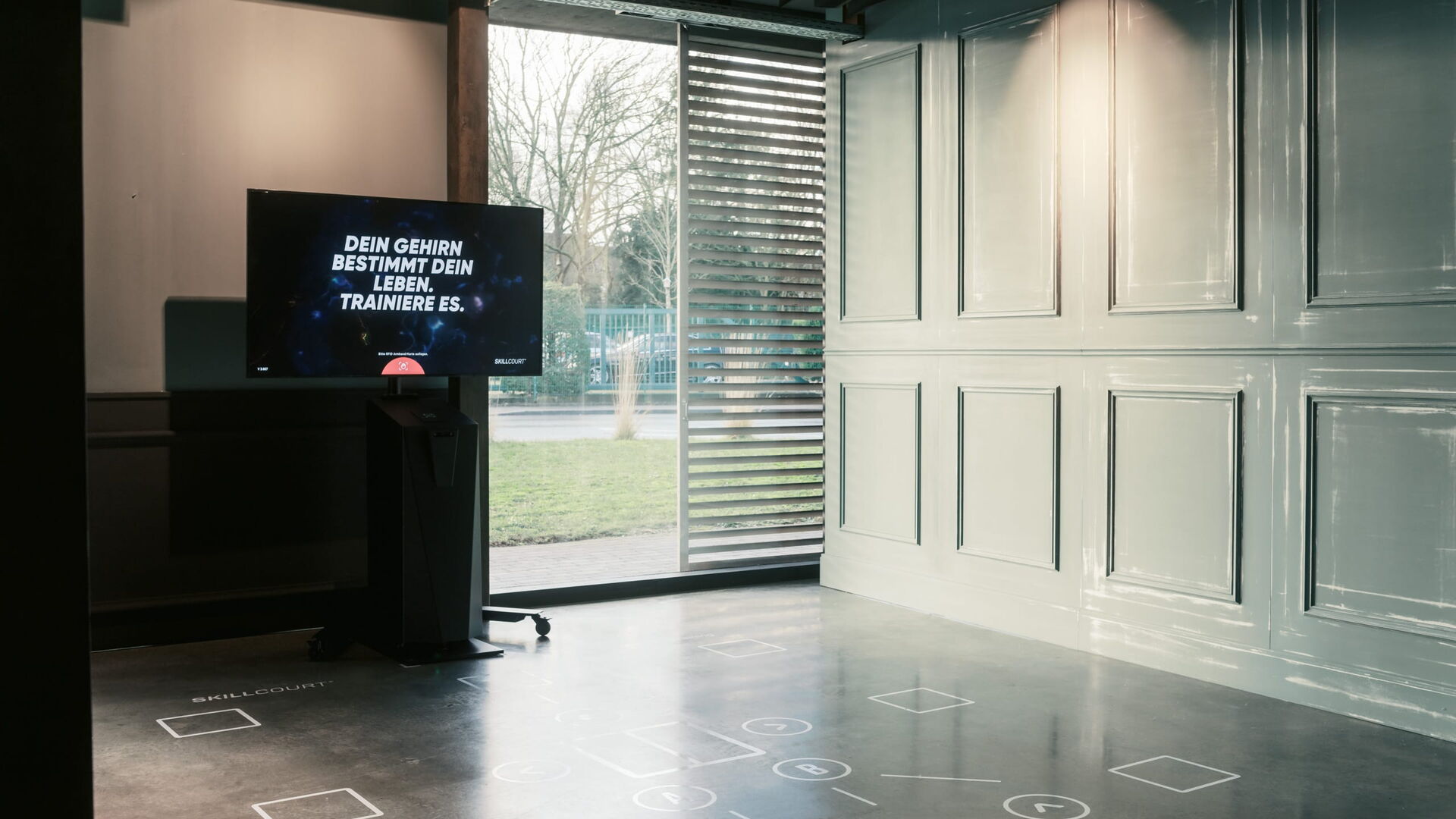 Ein moderner Raum in Bochum zeigt ein interaktives Display zur Förderung von Fitness und Gehirntraining.