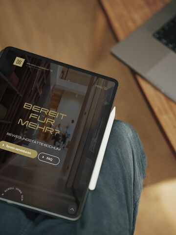 Ein Tablet zeigt die Webseite einer Physiotherapie in Bochum, die Training und Yoga anbietet, auf einem Holztisch.